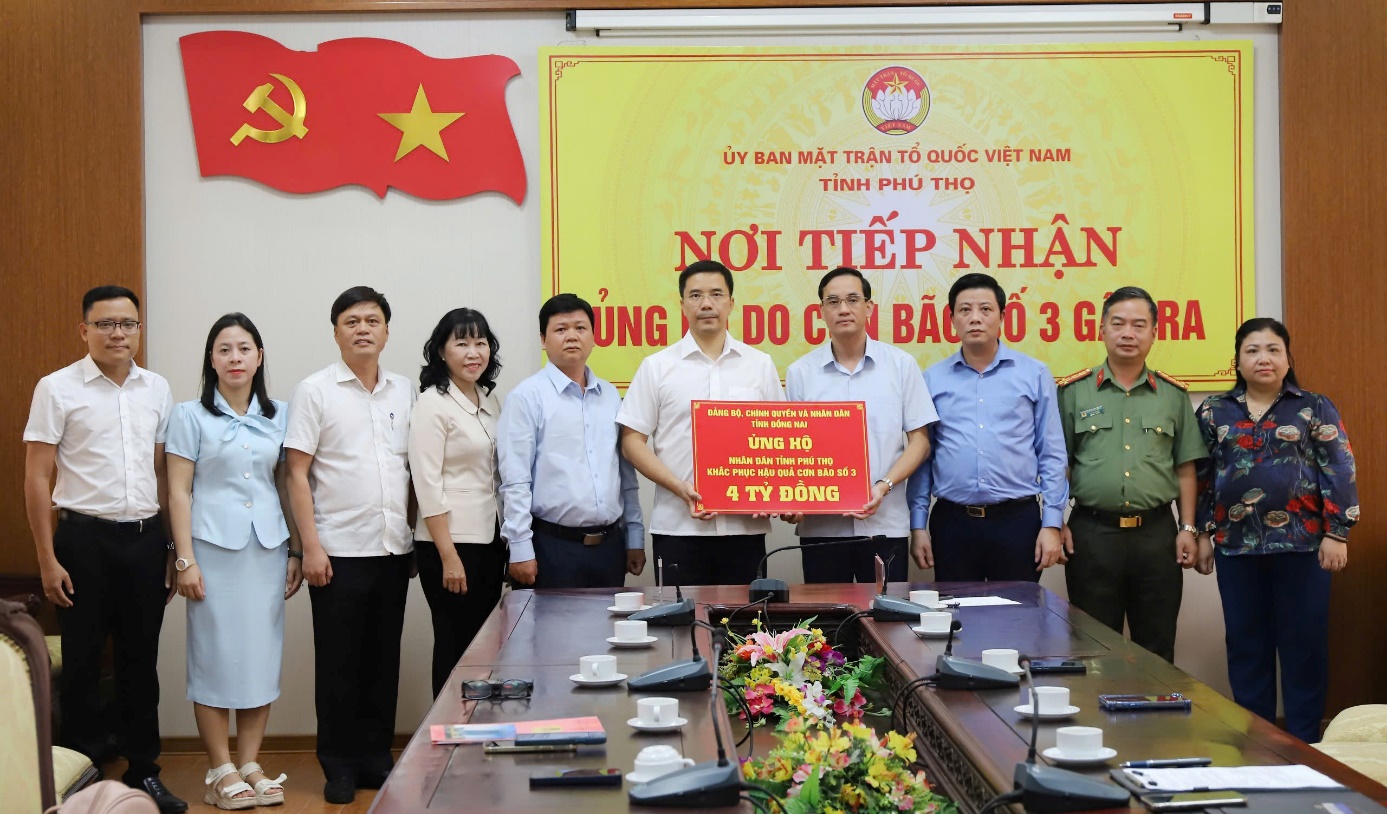 A group of people standing in front of a table with a signDescription automatically generated
