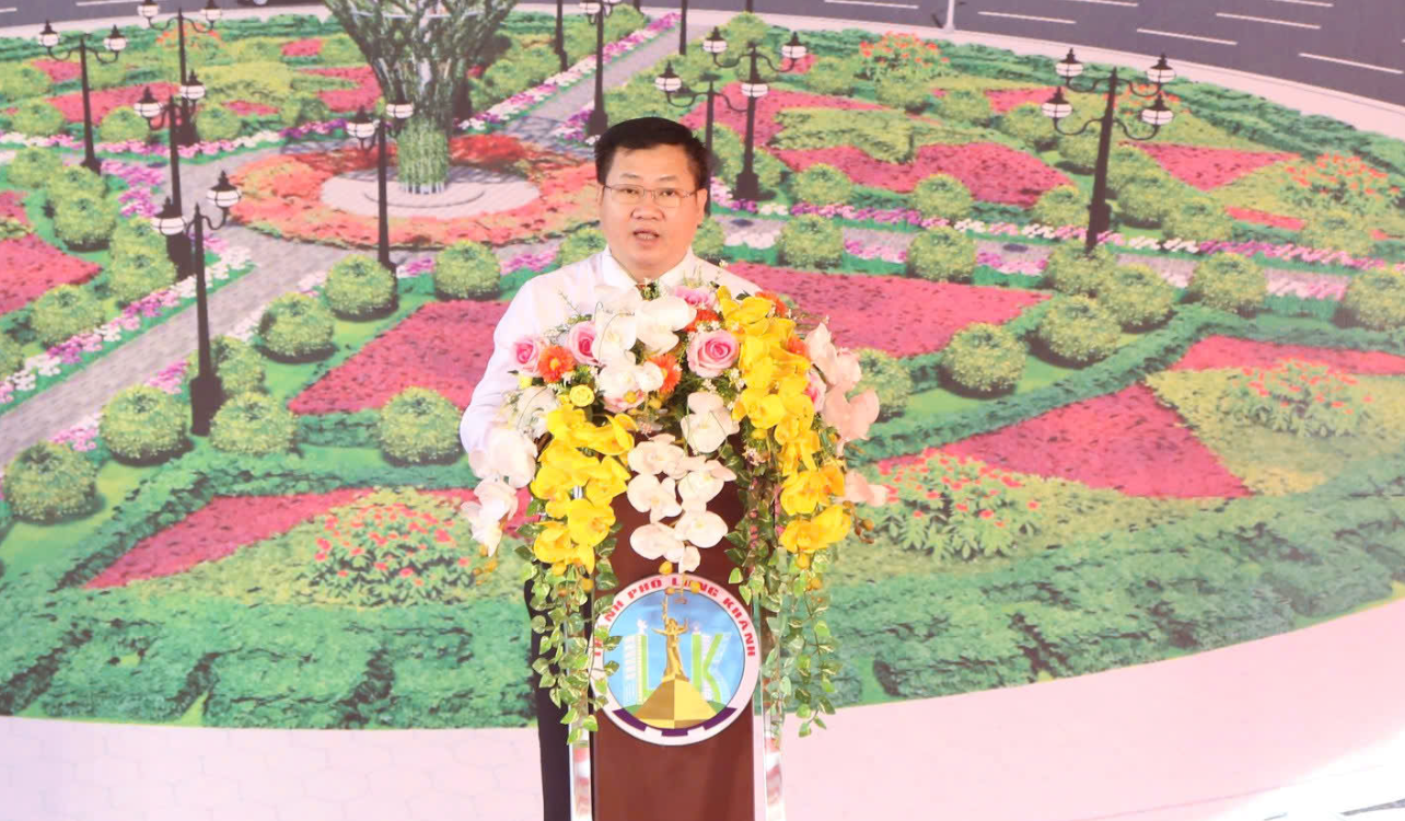 A person standing at a podium with flowersDescription automatically generated