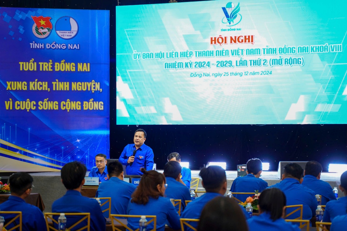 A group of people sitting in front of a large screenDescription automatically generated