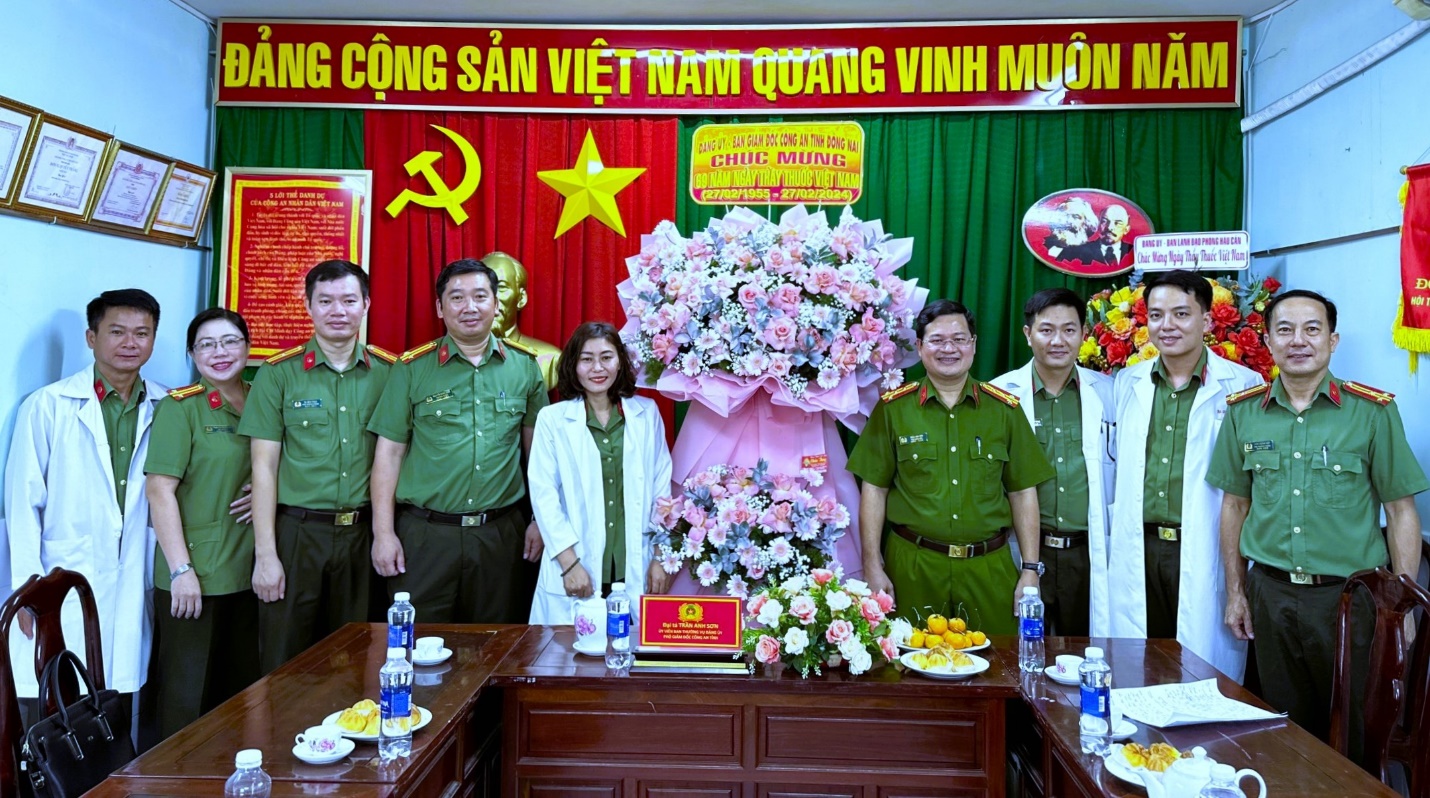 A group of people standing in front of a table with flowersDescription automatically generated