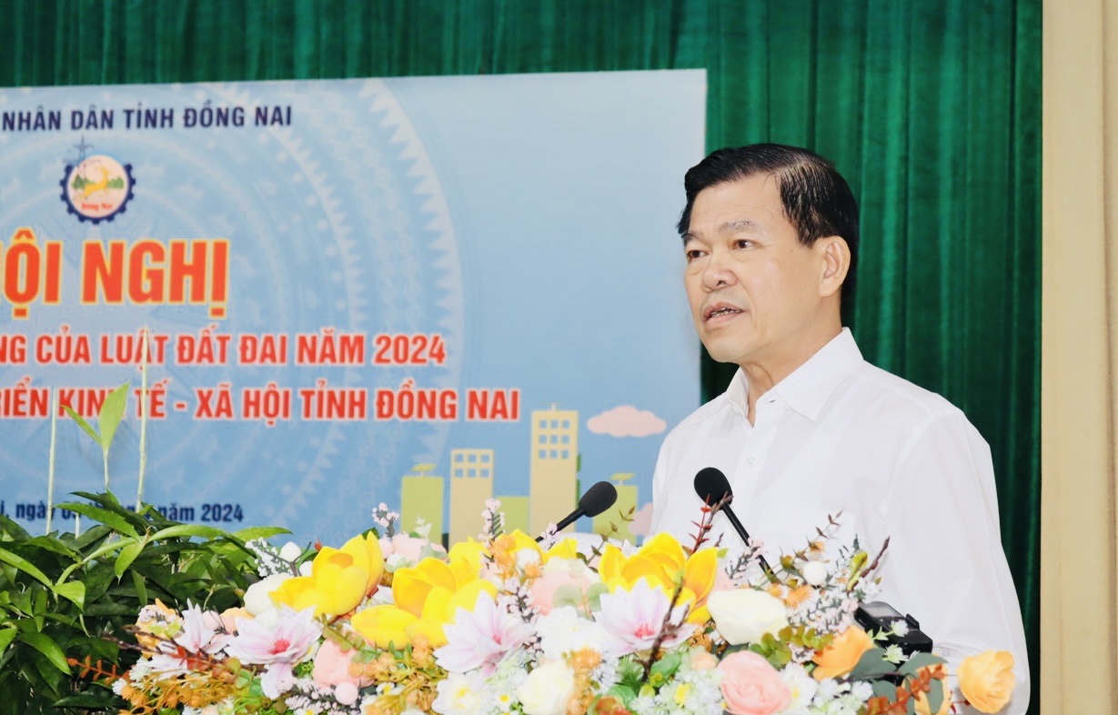 A person standing at a podium with flowersDescription automatically generated