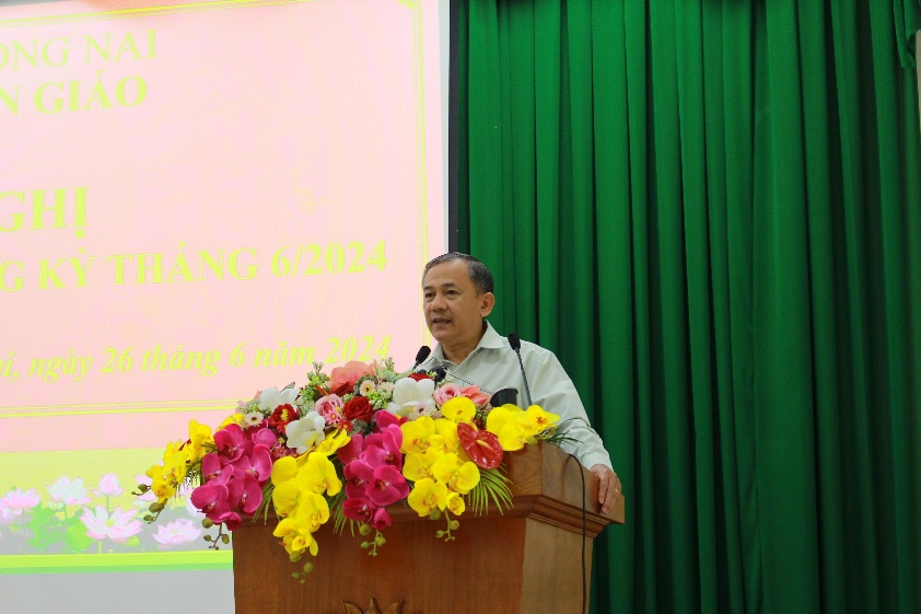 A person standing at a podium with flowersDescription automatically generated