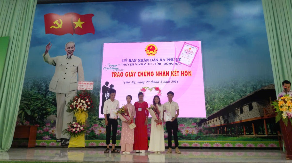 A group of people standing in front of a large screenDescription automatically generated