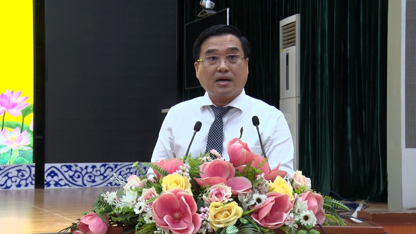 A person standing behind a podium with flowersDescription automatically generated