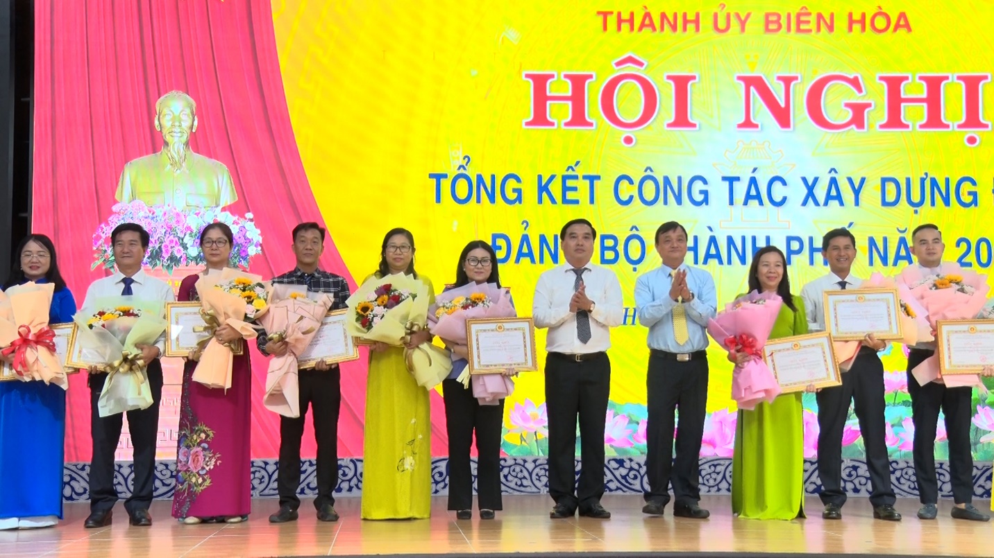 A group of people holding flowers and certificatesDescription automatically generated